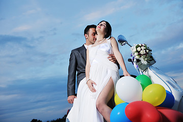 Image showing just married couple on the beach ride white scooter