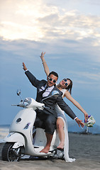 Image showing just married couple on the beach ride white scooter