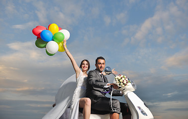 Image showing just married couple on the beach ride white scooter