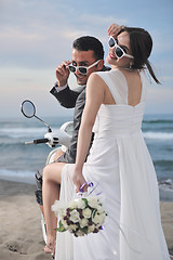 Image showing just married couple on the beach ride white scooter