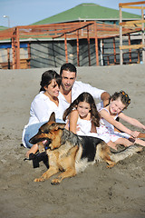 Image showing happy family playing with dog on beach