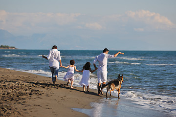 Image showing happy family playing with dog on beach