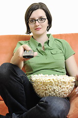 Image showing young woman eat popcorn on orange sofa