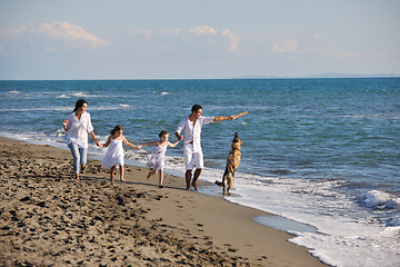 Image showing happy family playing with dog on beach