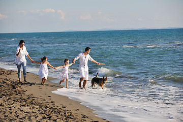 Image showing happy family playing with dog on beach