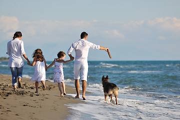 Image showing happy family playing with dog on beach