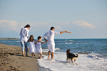 Image showing happy family playing with dog on beach