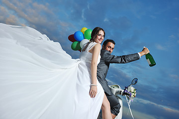 Image showing just married couple on the beach ride white scooter