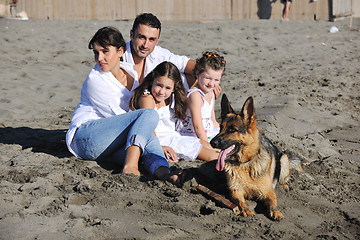 Image showing happy family playing with dog on beach