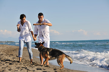 Image showing happy family playing with dog on beach