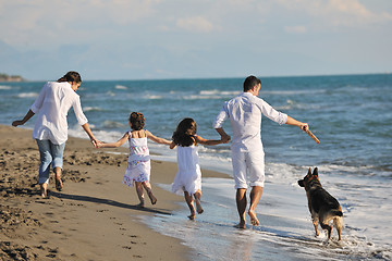 Image showing happy family playing with dog on beach