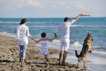 Image showing happy family playing with dog on beach