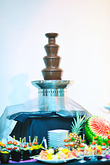 Image showing liquid chocolate fountain and fresh fruits on stick