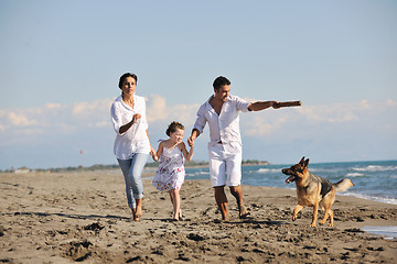 Image showing happy family playing with dog on beach