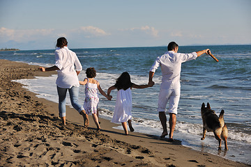 Image showing happy family playing with dog on beach