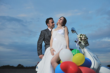 Image showing just married couple on the beach ride white scooter