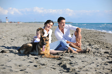 Image showing happy family playing with dog on beach