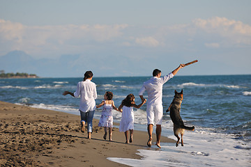 Image showing happy family playing with dog on beach