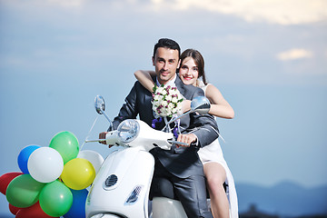 Image showing just married couple on the beach ride white scooter