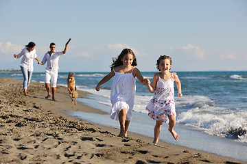 Image showing happy family playing with dog on beach