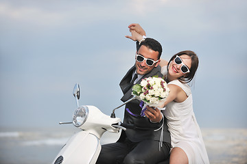 Image showing just married couple on the beach ride white scooter