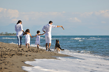 Image showing happy family playing with dog on beach