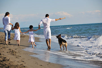 Image showing happy family playing with dog on beach