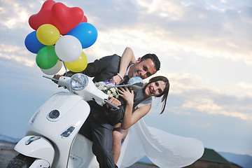 Image showing just married couple on the beach ride white scooter