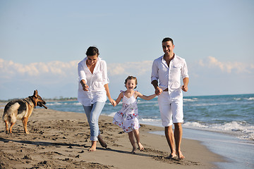 Image showing happy family playing with dog on beach