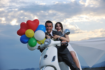 Image showing just married couple on the beach ride white scooter