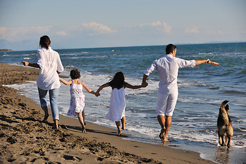 Image showing happy family playing with dog on beach