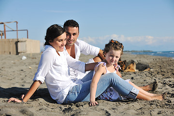 Image showing happy family playing with dog on beach