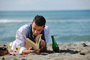 Image showing man reading book at beach