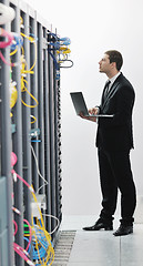 Image showing businessman with laptop in network server room