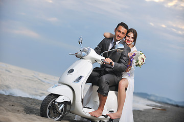 Image showing just married couple on the beach ride white scooter