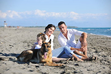 Image showing happy family playing with dog on beach