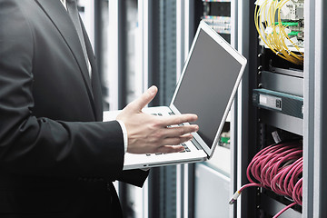 Image showing businessman with laptop in network server room