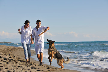 Image showing happy family playing with dog on beach