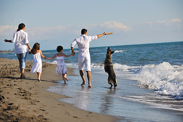 Image showing happy family playing with dog on beach