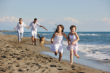 Image showing happy family playing with dog on beach