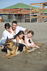 Image showing happy family playing with dog on beach