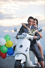 Image showing just married couple on the beach ride white scooter