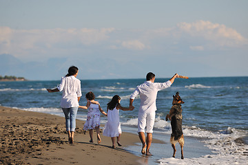 Image showing happy family playing with dog on beach