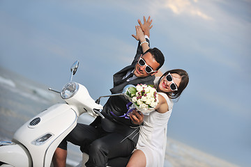 Image showing just married couple on the beach ride white scooter