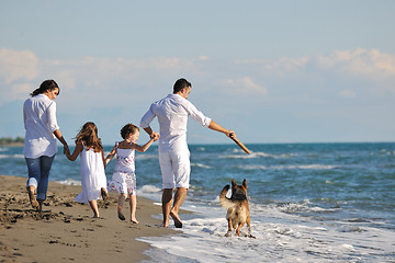 Image showing happy family playing with dog on beach