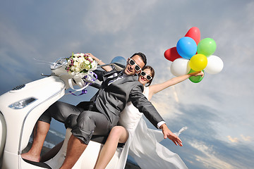 Image showing just married couple on the beach ride white scooter