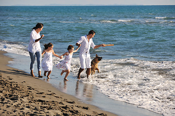 Image showing happy family playing with dog on beach