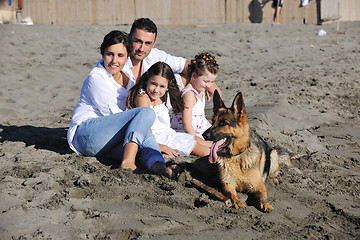 Image showing happy family playing with dog on beach