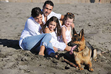 Image showing happy family playing with dog on beach