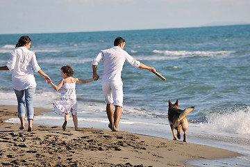 Image showing happy family playing with dog on beach